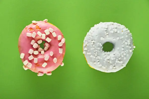 Dos rosquillas esmaltadas redondas sobre papel verde —  Fotos de Stock