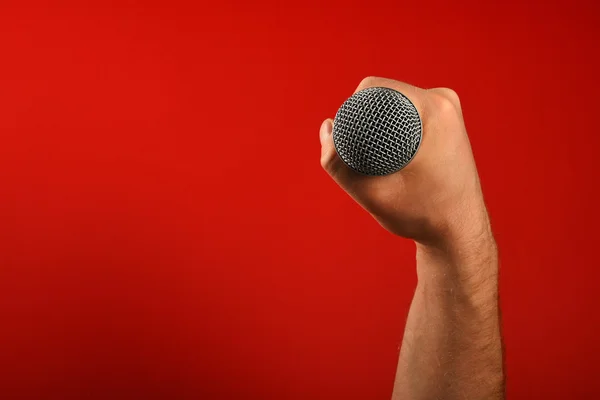Man hand with microphone over red background — Stock Photo, Image
