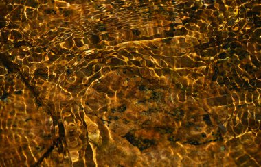 Altın su dalgaları taşların üzerinde çalışan