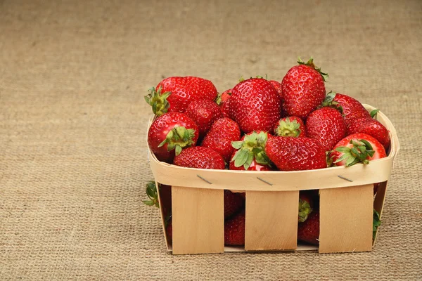 Strawberry in wooden basket on jute canvas — Stock Photo, Image