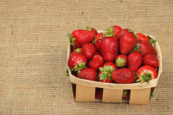 Erdbeere im Holzkorb auf Jute-Leinwand — Stockfoto