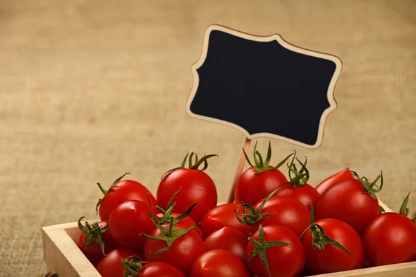 Tomates rojos en caja con cartel de precio sobre lienzo — Foto de Stock