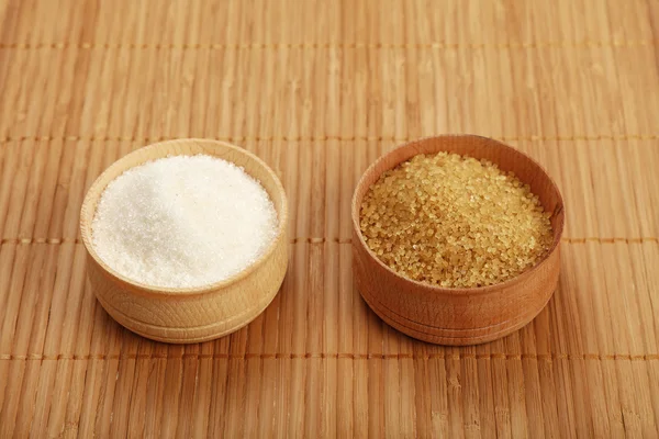 Білий і коричневий тростинний цукор в дерев'яних мисках на килимку — стокове фото
