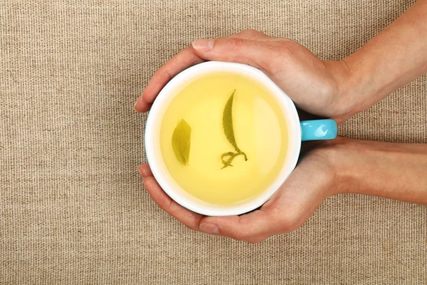 Due mani di donna che tengono la tazza piena di tè verde — Foto Stock