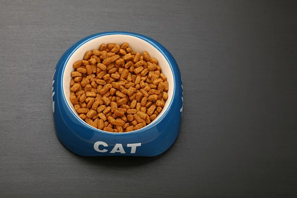 Trockenfutter für Katzen in Keramikschale auf schwarzem Boden — Stockfoto