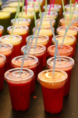 Birçok plastik bardakta taze meyve ve sebze suyu ve smoothie 'yi perakende satış mağazasında pipet içerek, yüksek açılı manzarayla kapatın.