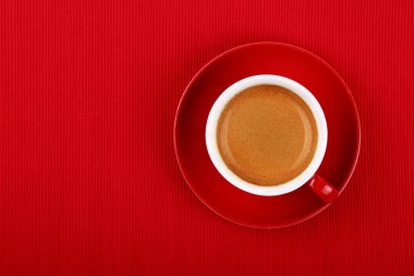 Bir fincan espresso kahveyi kırmızı masa örtüsünün üzerine koy, üst manzaranın üstüne, tam üstüne.