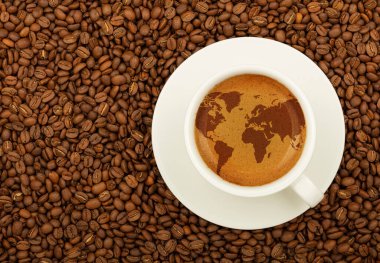 Beyaz fincanı çay tabağına kapat, dünya haritalı espresso kahvesi köpüklü krema, kavrulmuş kahve çekirdeklerinin üstünde, üst manzaranın tam üstünde,