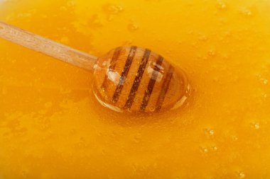 Bir ahşap bal kaşığını bir kase taze sıvı akasya ile kapat tatlım, yüksek açılı görüş.