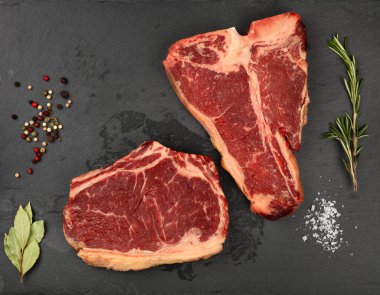 Kapatın mermer, çiğ pirzola ve biftek... siyah tahtada biftek... baharatlarla birlikte kesme tahtası, üst manzara... tam da üstte.