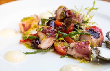 Izgara deniz ürünleri, ahşap masada beyaz tabakta sıcak salata, yüksek açılı manzara.