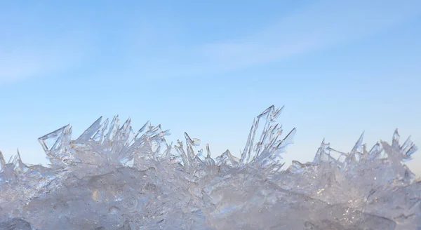 Close up lacy ice crystals pattern over clear blue sky background, low angle view