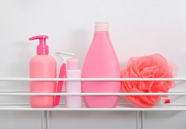 Güzellik ve kişisel hijyen ürünlerinden oluşan pembe şişeleri kapat, kadın tıraş seti, beyaz banyo arka planında banyo rafı, düşük açılı görünüm.