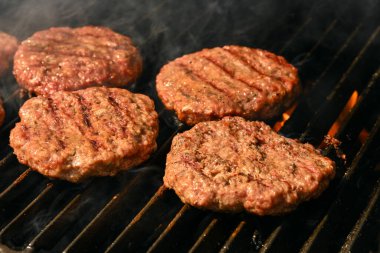 Közleme ve tütsüleme sığır eti ya da domuz eti barbeküsü hamburgerler için bbq alev ızgarasında dökme demir ızgaralı, yüksek açılı manzaralı