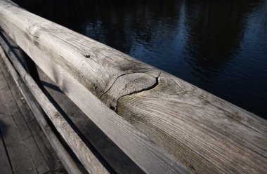 Wooden bridge handrail diagonal shot with blue water background