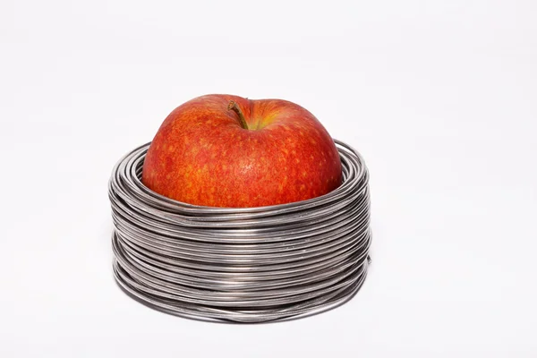 Manzana con cable: manzana roja entera en bobinas de alambre de aluminio aislado sobre fondo blanco — Foto de Stock