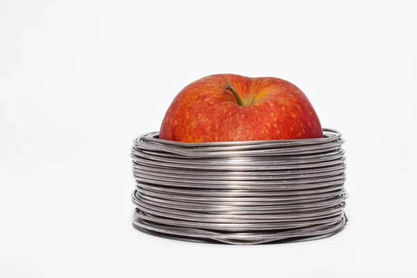 Wired apple: whole red apple in coils of aluminum wire isolated on white background — 스톡 사진