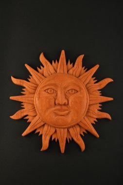 Mexican wooden carved Mayan sun symbol plate isolated on black