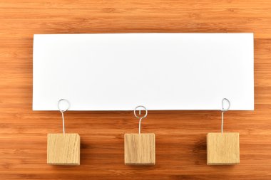 One paper note with three holders isolated on wooden background