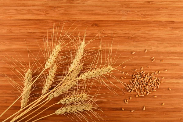 Wooden bamboo cutting board with nine wheat ears and grains — Stock Photo, Image