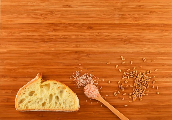 Cutting board with spoon of Himalayan  salt, wheat grains and br — Stock Photo, Image