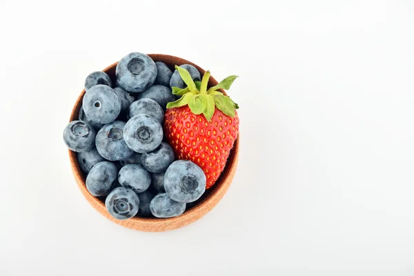 Blueberries and one strawberry in wooden bowl isolated on white — Stock Photo, Image