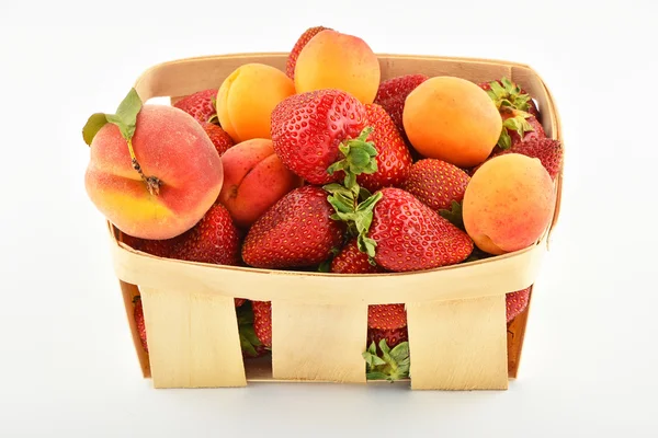 Jordgubbar, aprikoser och persikor i trä korg isolerad på wh — Stockfoto