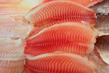Meşgul bir balık pazarında buzda sergilenen taze tilapia balığı filetoları, en iyi deniz ürünlerini arayan müşterilere yüksek kalitede yiyecek sağlıyor.