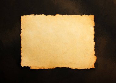 Close up stack of several blank old antique vintage brown paper parchment sheets with aged and weathered edges over dark table background