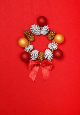 Kırmızı keçeli arka planı, fotokopi alanı, masa üstü manzarası, düz uzanmış beyaz ve altın renkli koni Noel çelenklerini kapatın.