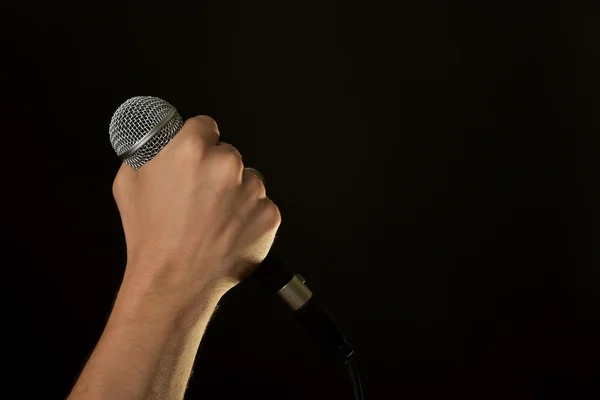 Male hand with microphone isolated on black — Stock Photo, Image