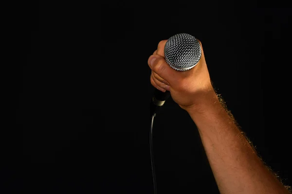 Mano maschile con microfono isolato su nero — Foto Stock