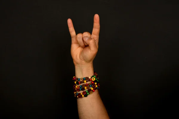 Hand with devil horns and colorful beads isolated on black — Stock Photo, Image