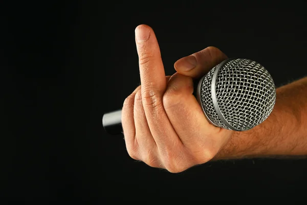 Hand with microphone and fuck off finger on black — Stock Photo, Image