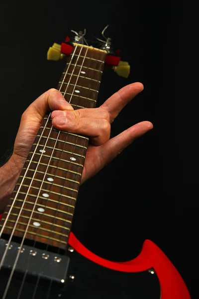 Рука з червоною гітарою і диявольськими рогами ізольовані на чорному — стокове фото