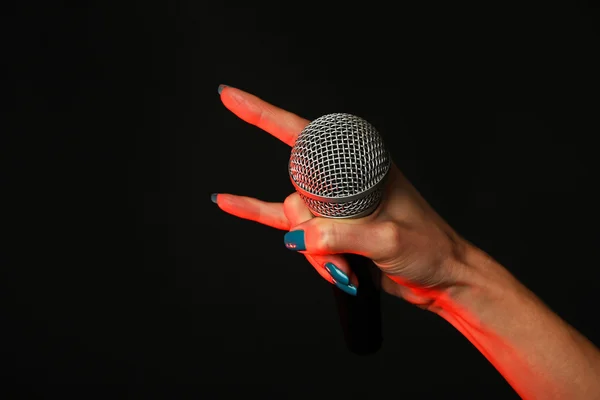 Mano donna con microfono e corna diavolo su nero — Foto Stock
