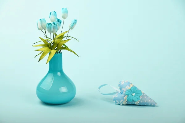 Coração de brinquedo e vaso com tulipas de seda no fundo azul — Fotografia de Stock