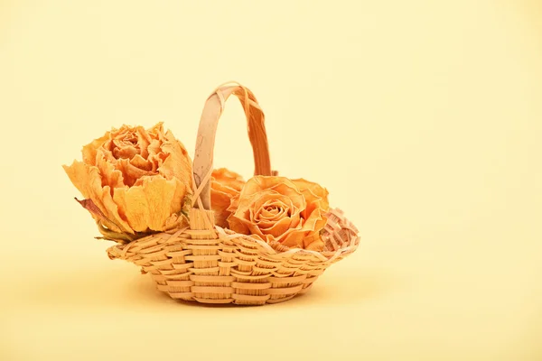 Small basket of dried roses on beige paper — Stock Photo, Image