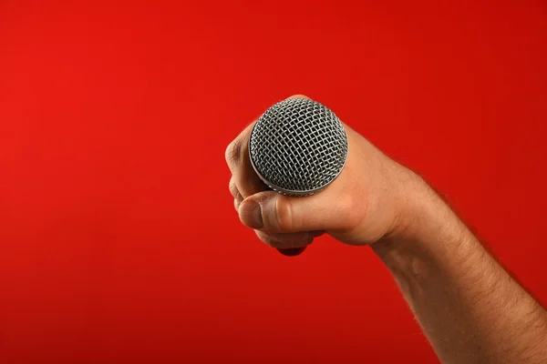 Mano uomo con microfono su sfondo rosso — Foto Stock