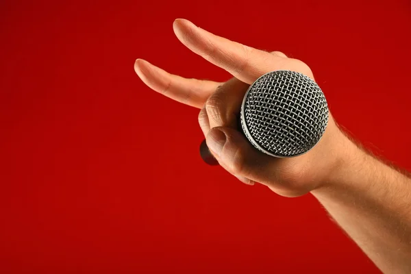 Man hand with microphone and devil horns over red — Stock Photo, Image