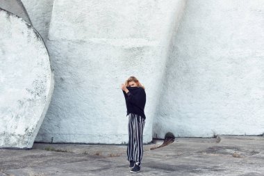 Sarışın, binanın duvarının yanında poz veriyor.