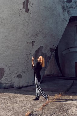 Sarışın, binanın duvarının yanında poz veriyor.