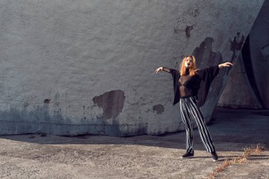 Sarışın, binanın duvarının yanında poz veriyor.