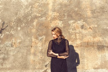 Sarışın, binanın duvarının yanında poz veriyor.