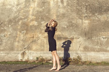 Sarışın, binanın duvarının yanında poz veriyor.