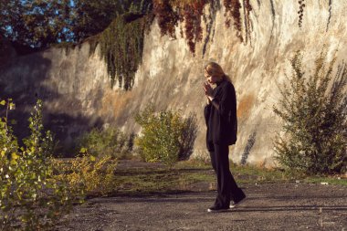 Sarışın, binanın duvarının yanında poz veriyor.