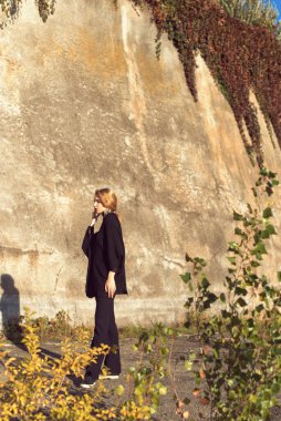 Sarışın, binanın duvarının yanında poz veriyor.