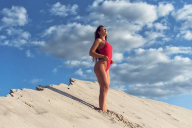 Esmer, tek parça mayo içinde tatilde.