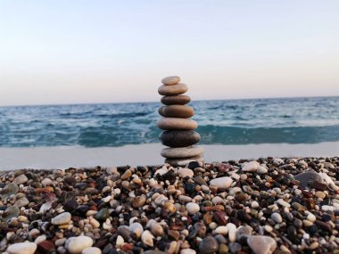 Sahilde taşlardan yapılmış denge sanatı. Arka planda Akdeniz.