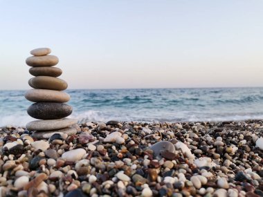 Sahilde taşlardan yapılmış denge sanatı. Arka planda Akdeniz.